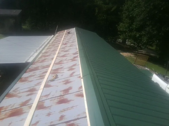 Old rusted panels beside newly installed green metal roofing — Wind Damage Roof Repair by Roofing Brothers in Broad Run