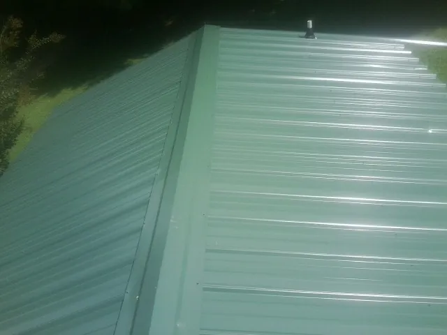 New green metal panels meeting at the ridge of a roof — Flat Roof Repair work by our crew in Broad Run