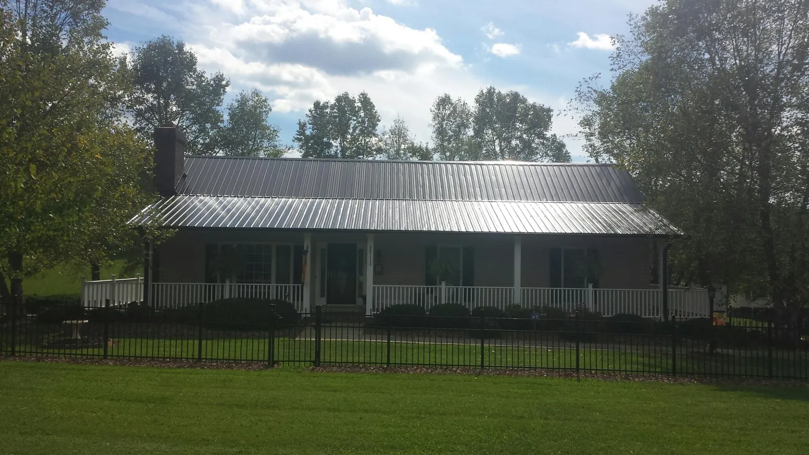 Gray metal roof on a brick ranch with a full width front porch — Gutter Guard Installation work by our crew in Broad Run