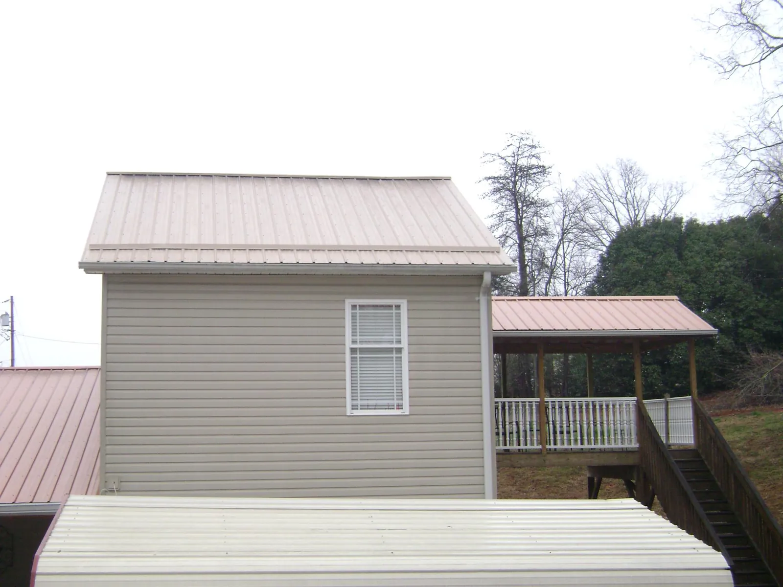 Tan metal roofs on a two story addition and attached porch, from a Roof Replacement job in Broad Run