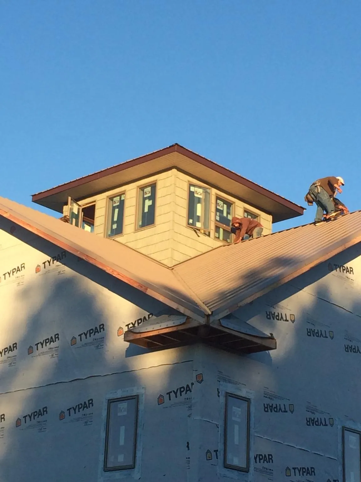 Roofers working around a rooftop cupola on a new metal roof at sunset — Roof Waterproofing in Broad Run by Roofing Brothers